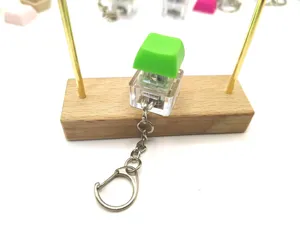 Detailed view of a green mechanical keyboard switch fidget toy keychain on wood