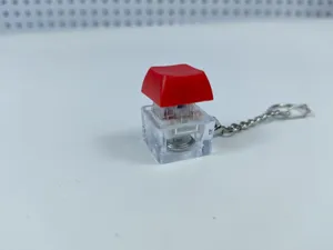 Mechanical keyboard switch keychain, glowing clear housing red keycap stress relief toy.