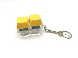 Stress relief fidget toy keychain featuring two yellow mechanical switch keycaps on clear base