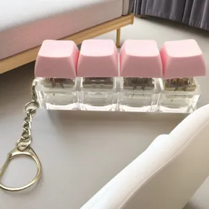 Close-up of four-key mechanical keyboard switch keychain with pink keycaps and clear base.