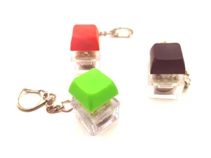 Close-up of three glowing mechanical keyboard switch keychains in red green and blue colors