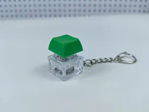 Detail view of a glowing mechanical keyboard switch keychain with green keycap and clear case.