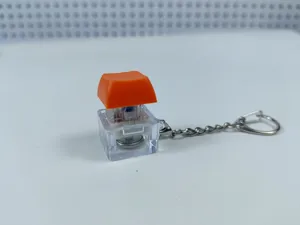 Transparent mechanical keyboard switch fidget toy keychain with colorful glowing light.