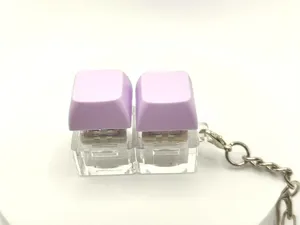 Close-up detail of purple dual keycap mechanical switch keychain with clear base and metal ring.