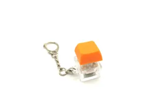 Detailed view of a clear mechanical keyboard switch keychain with an orange keycap