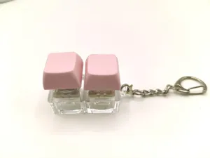Close-up detail of a cute pink mechanical keyboard switch keychain with a metal ring.