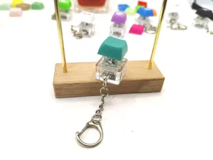 Close-up view of a teal green mechanical keyboard switch keychain for stress relief