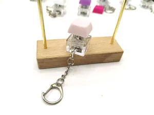 Detailed close-up of a high-transparency mechanical keyboard switch keychain with pink keycap