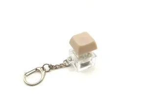 Luminous mechanical keyboard switch fidget toy keychain with transparent base and beige keycap.