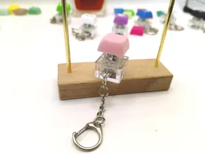 Detailed macro view of a pink mechanical keycap switch keychain displayed on a wooden stand
