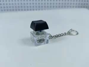 Mechanical keyboard switch keychain with clear base and black keycap for stress relief.