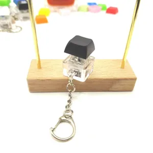 Mechanical switch fidget keychain with black keycap and transparent base on wooden stand