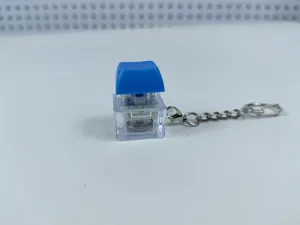 Close-up detail shot of the glowing mechanical keyboard switch keychain with blue keycap.