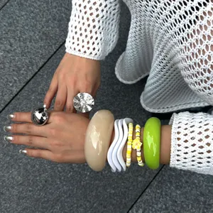 Nahaufnahme von stapelbaren bunten Macaron-Resin-Armbändern und großen Silberringen