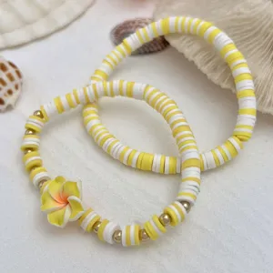 Detaillierte Makroansicht von gelb-weißen Heishi-Perlenarmbändern mit gelber Blumenverzierung