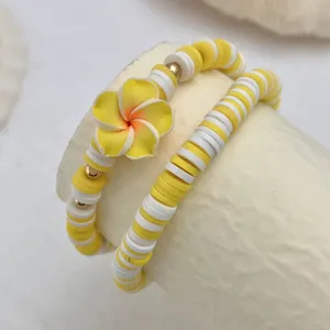 Detailansicht von gelb-weißen Macaron-Resin-Perlenarmbändern mit Blumenanhänger.