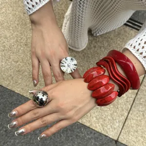Detailansicht modischer roter Marmorarmbänder und silberner Kugelringe an den Händen