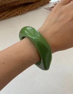 Minimalistischer grüner geometrischer klobiger Kunstharz-Armreif am Handgelenk einer Frau