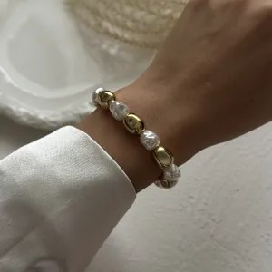 Elegant pearl and gold bead bracelet worn on wrist with white satin sleeve