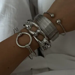 Primo piano di bracciali in argento minimalisti con catena spessa e stili a polsino