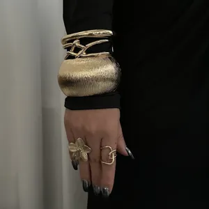Detailansicht modischer Metall-Armreif und Ringe Set in eleganter Goldoptik.
