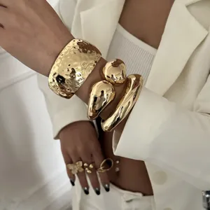 Detailaufnahme eines klobigen goldenen Armband-Sets mit Tropfen- und Hammerschlagoptik.