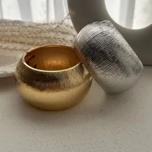 Detailaufnahme von strukturierten gold- und silbernen Metall-Armreifen mit Feder