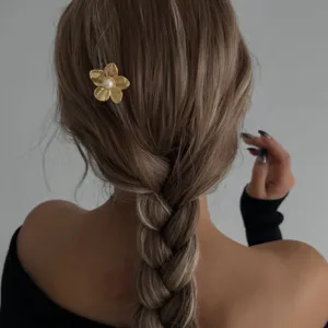 Nahaufnahme einer goldenen Blumen-Haarnadel mit Perle in einer geflochtenen Frisur