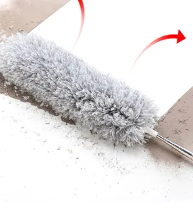 Detail of a grey microfiber duster cleaning thick dust with a telescopic stainless steel handle