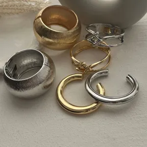 Detailaufnahme von massiven, gold- und silberfarbenen Metallarmreifen und Manschetten-Sets