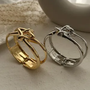 Nahaufnahme von goldenen und silbernen Metallarmreifen mit schickem Knotendesign und Feder.