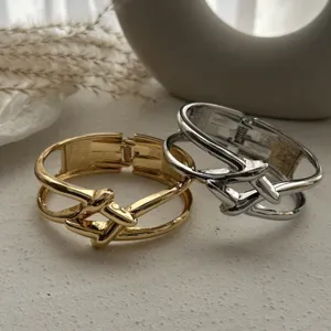 Detaillierte Ansicht von polierten Metallarmreifen in Gold und Silber mit Knotendesign