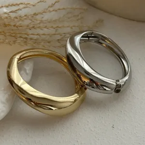 Nahaufnahme ineinandergreifender gold- und silberner Wassertropfen-Armreifen