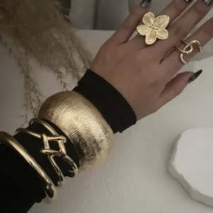 Detailansicht eines klobigen Gold-Schmucksets mit breiter Manschette und Blumenring.