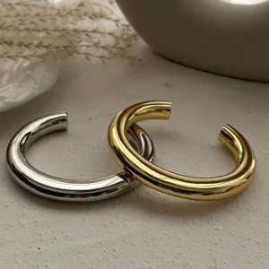 Nahaufnahme von klobigen gold- und silberfarbenen Metall-Armreifen mit Hochglanzfinish.
