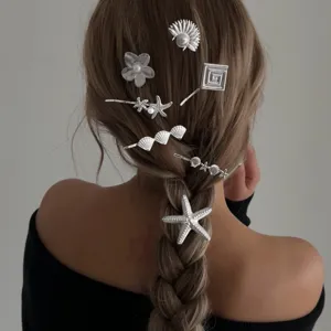 Detailansicht eleganter silberner Seestern- und Muschelhaarnadeln in einer Flechtfrisur.