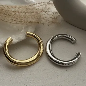 Detailansicht dicker goldener und silberner C-förmiger Armreifen im minimalistischen Design.