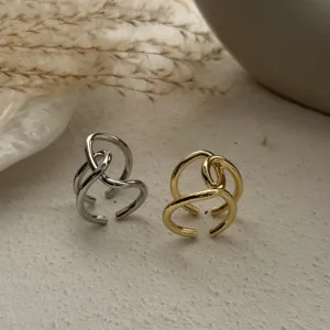 Detailansicht von zwei minimalistischen, ineinander verschlungenen Metallringen in Gold und Silber