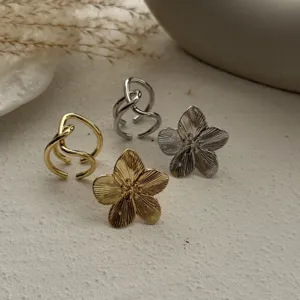 Detailansicht modischer gold- und silberfarbener Metallringe mit geschwungenen Blumenmustern