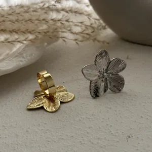 Nahaufnahme von Gold- und Silberringen mit strukturiertem Blumendesign in weicher Umgebung.