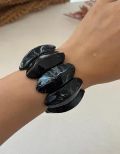 Detailansicht eines klobigen schwarzen Armbands mit Marmormuster und glänzendem Finish.