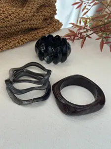 Detailaufnahme von klobigen Harz-Armreifen in dunkler Marmor- und Burgunder-Optik.