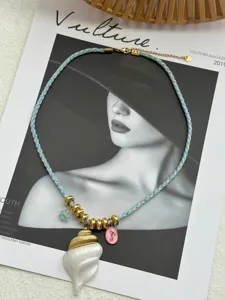 Detailed macro view of a woven necklace with a white conch shell and gold charms.