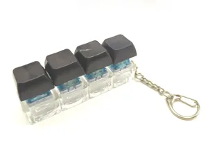 Mechanical keyboard switch fidget keychain pendant with black keycaps and clear base.