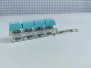 Detail view of the four-key mechanical switch keychain featuring clear housing and blue keycaps.