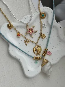 Close-up of vintage 14k gold plated necklaces with sun, moon, and conch pendants