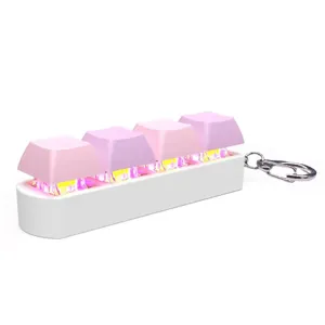 Detail view of pink mechanical keyboard keycap keychain with glowing LED lights