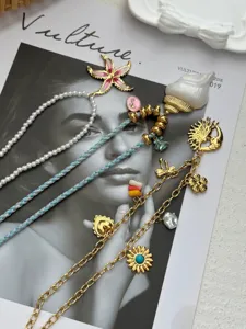 Detail view of summer vacation layered gold necklaces with shell and sun charms on a magazine