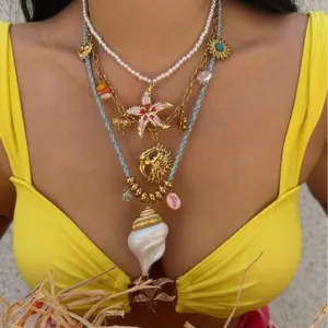 Vintage gold layered necklaces featuring summer charms and a large white conch shell pendant