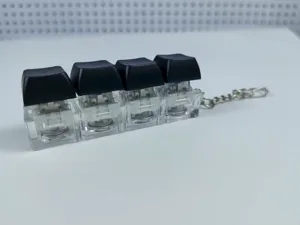 4-key mechanical keyboard switch fidget toy keychain with black keycaps and clear base.